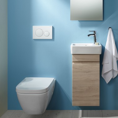 An einer hellblauen Wand ist ein wandhängendes Renova Plan WC und ein Waschplatz angebracht