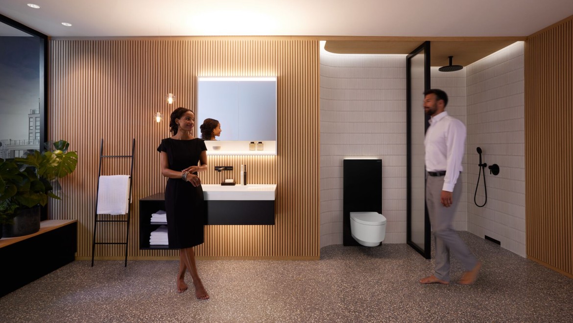Mann und Frau im harmonisch beleuchteten Badezimmer mit Geberit ONE Produkten