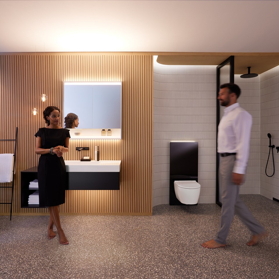 Mann und Frau im harmonisch beleuchteten Badezimmer mit Geberit ONE Badmöbeln und Keramiken (© Geberit)