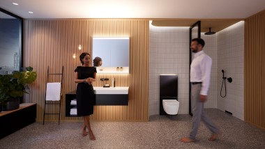 Mann und Frau im harmonisch beleuchteten Badezimmer mit Geberit ONE Badmöbeln und Keramiken (© Geberit)