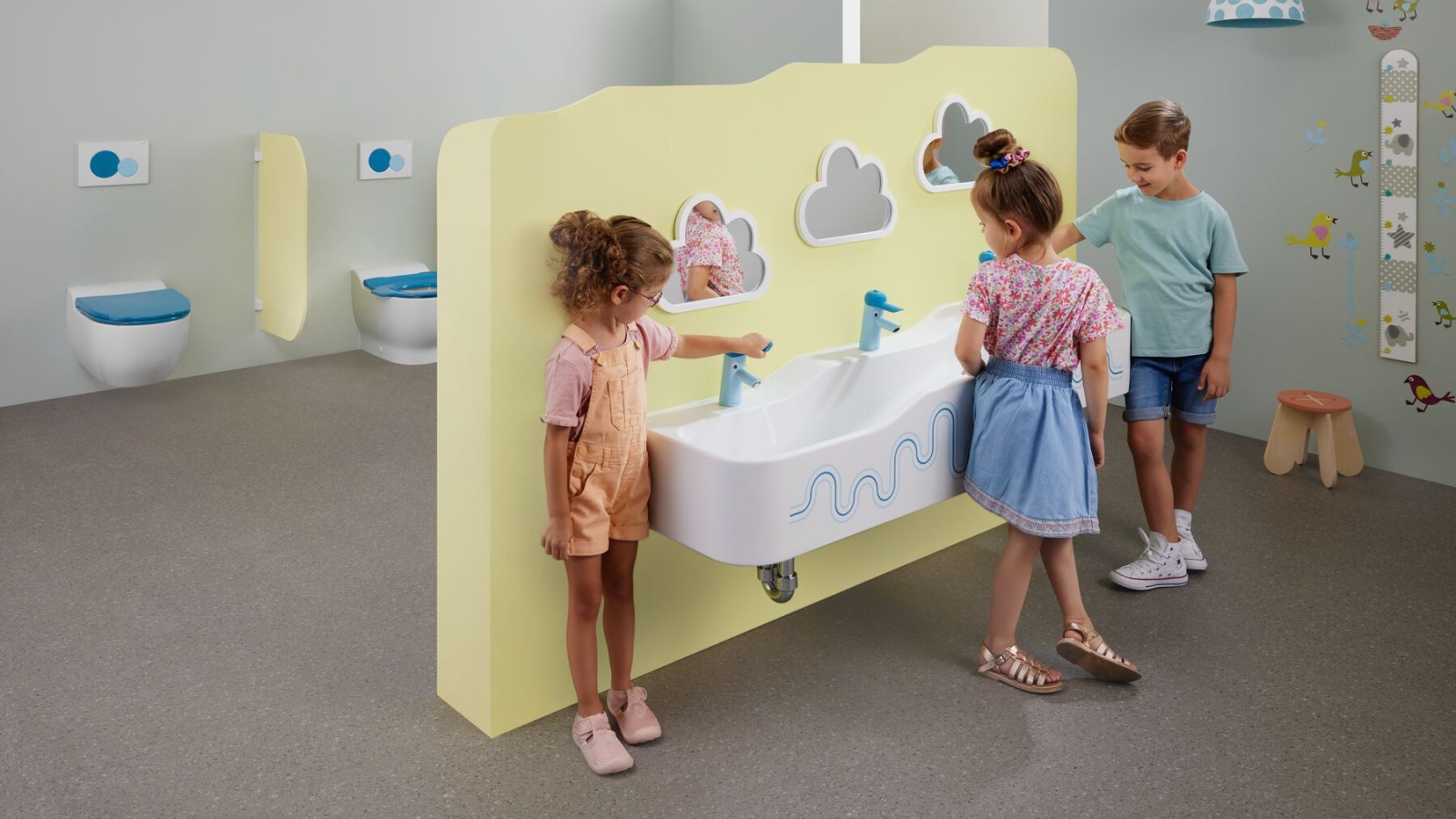 Kinder spielen in einem mit Geberit Bambini ausgestatteten Sanitärraum Kinder spielen in einem mit Geberit Bambini ausgestatteten Sanitärraum