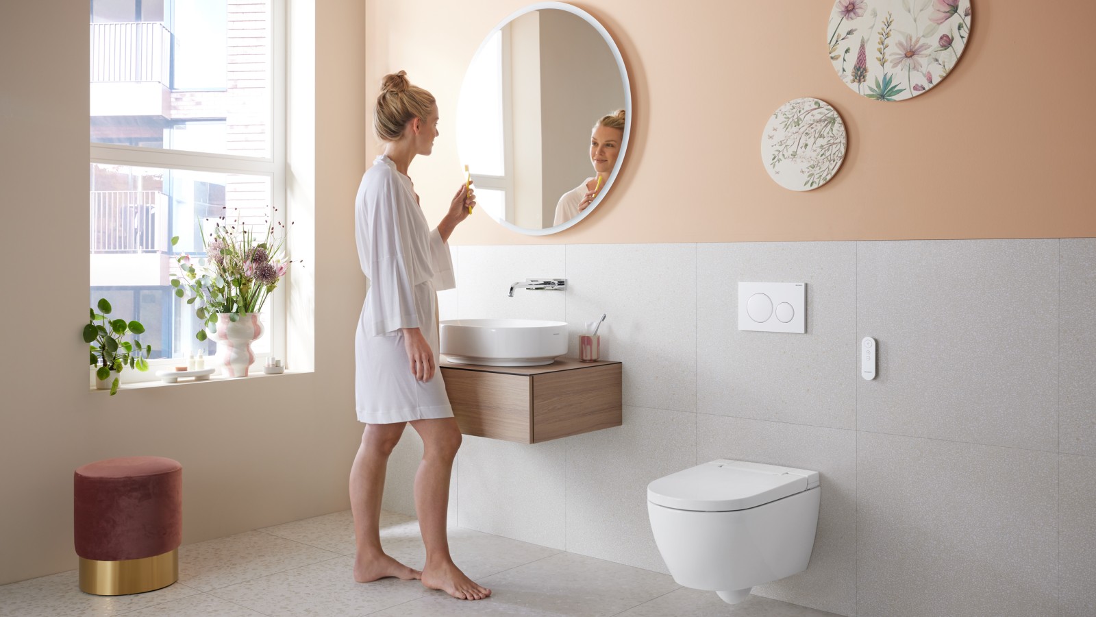 Frau in Badezimmer mit Geberit AquaClean Alba, einer kostengünstigen Toilette mit Waschfunktion Frau in Badezimmer mit Geberit AquaClean Alba, einer kostengünstigen Toilette mit Waschfunktion