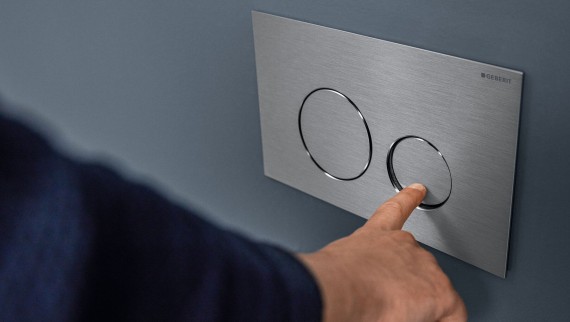 Hand löst kleine Spülung an der Sigma40 Round Betätigungsplatte aus (© Geberit)