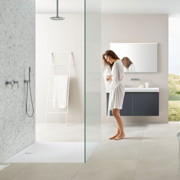 Frau in Bad mit Walk-in-Dusche und Geberit Olona Duschfläche Frau in Bad mit Walk-in-Dusche und Geberit Olona Duschfläche