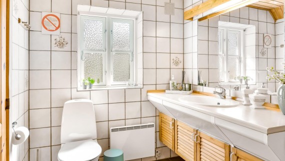 Das ursprüngliche Badezimmer mit bodenstehendem WC, weißen Kacheln und hölzernen Badmöbeln (© @triner2 und @strandparken3)