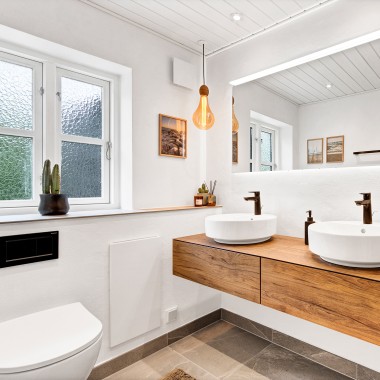 Helles, renoviertes Badezimmer mit zwei runden Waschbecken, einem grossen Spiegel und Badmöbeln aus Holz (© @triner2 und @strandparken3)