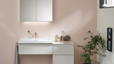 Ein Waschplatz mit Badmöbeln, Waschtisch und Spiegelschrank von Geberit vor einer pastellfarbenen Wand