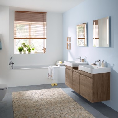 Ein Familienbad mit hellblauer Wand und Badmöbeln in Hickory, Spiegelschrank, Betätigungsplatte und Keramiken von Geberit Ein Familienbad mit hellblauer Wand und Badmöbeln in Hickory, Spiegelschrank, Betätigungsplatte und Keramiken von Geberit
